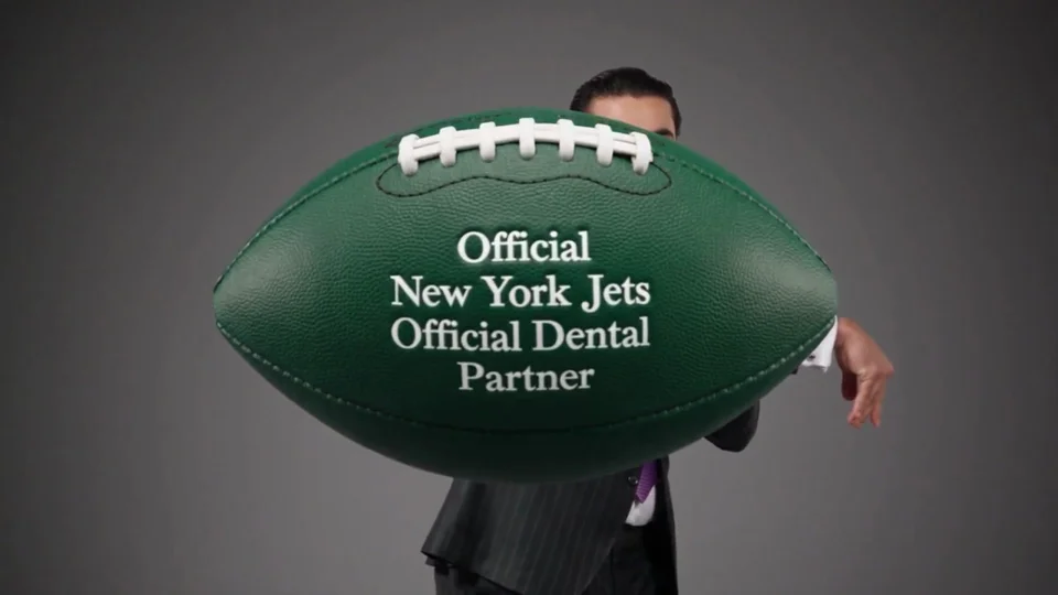 Generated scene of Dr. Avner with a green football reading Official New York Jets Official Dental Partner